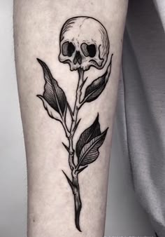 a black and white tattoo with a skull on it's leg, next to a rose