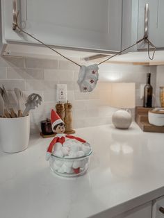 an elf is sitting on the kitchen counter next to a bowl of marshmallows