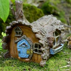 a small house made out of tree stumps in the forest with moss growing around it