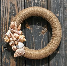 a wreath made out of rope and seashells is hanging on a wooden door