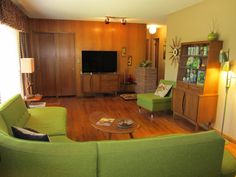 a living room filled with furniture and a flat screen tv on top of a wooden wall