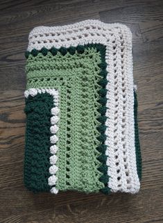 a green and white crocheted dishcloth sitting on top of a wooden table