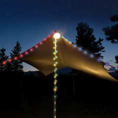 a large tent with lights on it and trees in the background