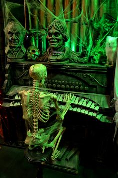 a skeleton sitting on top of a piano in front of a green light filled room