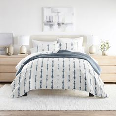 a bed with blue and white comforter in a bedroom next to two nightstands