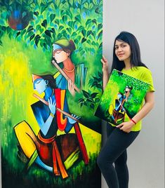 a woman standing next to a painting holding up two pieces of art on the wall