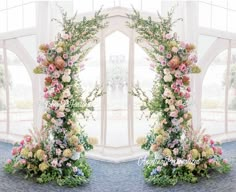 two floral archways are decorated with pink and yellow flowers, greenery and foliage