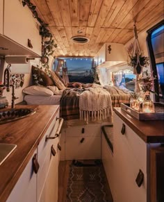 the interior of a camper van with wood ceiling and white cabinets, including a bed