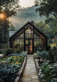 a house that is sitting in the middle of some plants and trees with sun shining on it