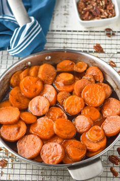 cooked carrots and pecans in a pan on a cooling rack with blue towel