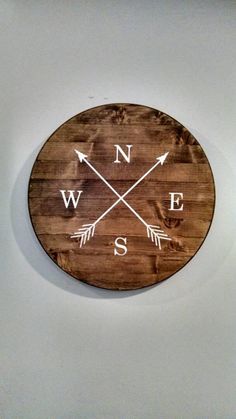 a wooden clock with arrows on the front and back of it that says n w e s