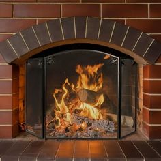 a fire burning in a brick fireplace next to a red brick wall and flooring