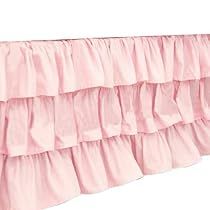 the pink ruffled bed skirt is hanging on a white wall and it's long