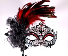 Masquerade mask, masquerade mask with stick and feathers, laser cut metal mask black and red crytals This a stunning masquerade metal laser cut mask with absolutely gorgeous rooster red feathers a black bow and a black stick  and red matching beautiful gems.  If you wish this same style and design of mask to be without the stick please feel free to contact me I will be happy to make the change!  In my store I have a large variety of masquerade metal laser cut mask for masquerade ball parties, I have lace machine embroidered masquerade mask I embroider too and if you wish for the thread to be changed to match the occasion please feel free to contact me anytime!  In my store I have other designs of masks and metal laser cut with different designs and colors of gems and masks also items that Red Fantasy Party Mask, Red And Black Masquerade Mask, Mask For Masquerade Ball, Quince Accessories, Masquerade Mask With Stick, Mask For Masquerade, Masquerade Mask Black, Masquerade Ball Party, Masquerade Wedding