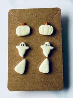 three white pumpkins and two ghost faces on a piece of brown crafting paper