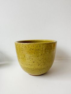 a yellow bowl sitting on top of a white table