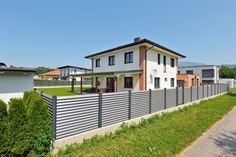 a house with a fence in front of it and some bushes on the other side