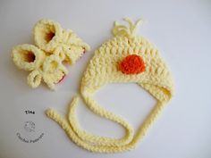 a crocheted hat and two pieces of fruit on a white surface with an orange dot