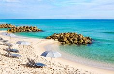 beach chairs and umbrellas are on the sand near the water