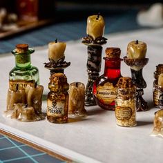 an assortment of miniature bottles and candles on a table