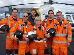 a group of people standing next to each other in front of a helicopter