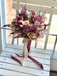 a bridal bouquet sitting on top of a white chair