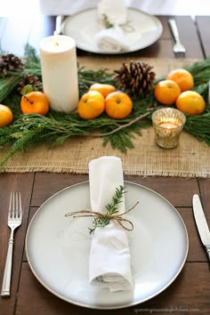 a place setting with oranges and pine cones