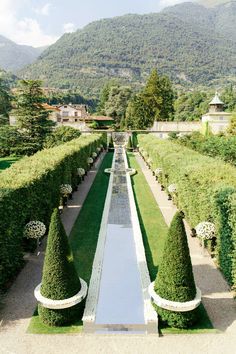 an aerial view of a formal garden with hedges and water feature in the foreground