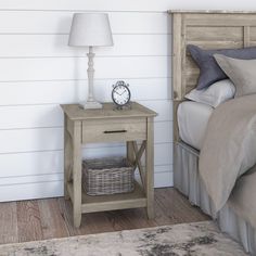 a nightstand with a clock on it next to a bed