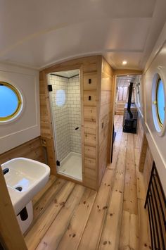 a bathroom with wood flooring and white sink in the corner next to an oval window