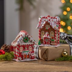 two gingerbread houses decorated with christmas decorations and candy canes on a wooden table