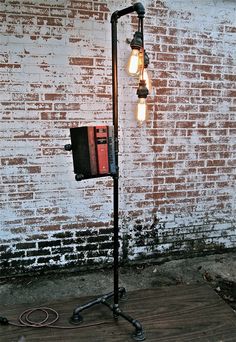 an old fashioned street light with three bulbs on it's stand next to a brick wall