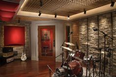 a drum set up in front of a brick wall with guitars and other musical equipment