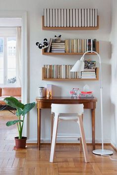 a desk with bookshelves on the wall above it and a lamp next to it