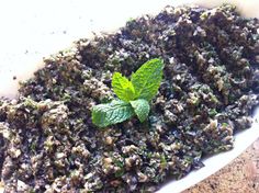 a white bowl filled with lots of green stuff and a leaf on top of it