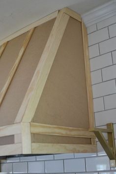 a close up of a stove top oven with wooden shelves above it and white tiles on the wall