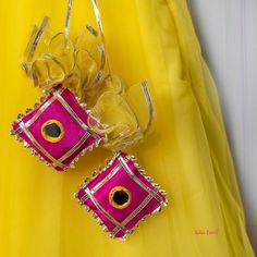 two yellow and pink bags with bows hanging from it's sides on a yellow dress