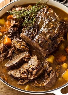 a pot filled with meat and vegetables on top of a wooden table