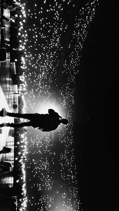 a person standing in the rain with an umbrella over their head and fireworks behind them