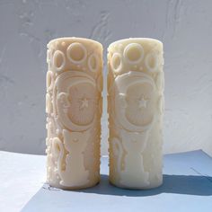 two white candles sitting next to each other on a table