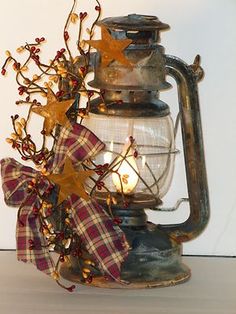 an old fashioned lantern is adorned with fall leaves and ribbon as well as a bow