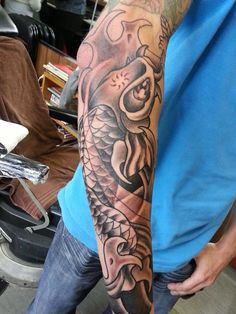 a man with a dragon tattoo on his arm is standing in front of a motorcycle