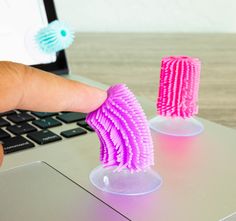 a person is holding two pink toothbrushes in front of a laptop computer that's turned on