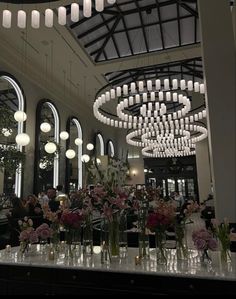 a large chandelier hanging from the ceiling in a dining room filled with tables and flowers