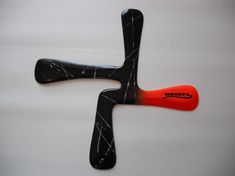 a black and red object with an orange handle sitting on top of a white surface