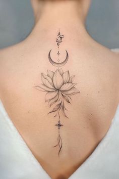 the back of a woman's neck with a lotus and crescent tattoo on it