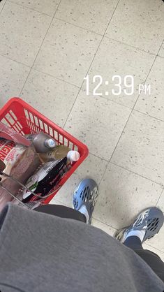 a person standing next to a shopping cart filled with bottles and other items on the floor