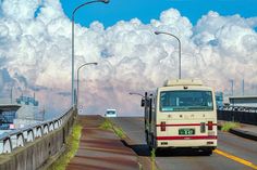 a bus driving down the road with clouds in the background