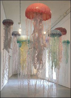 several jellyfishs hanging from the ceiling in an art gallery