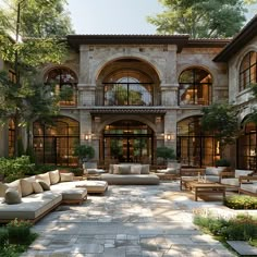 a large courtyard with couches and tables in front of an old building that is surrounded by greenery